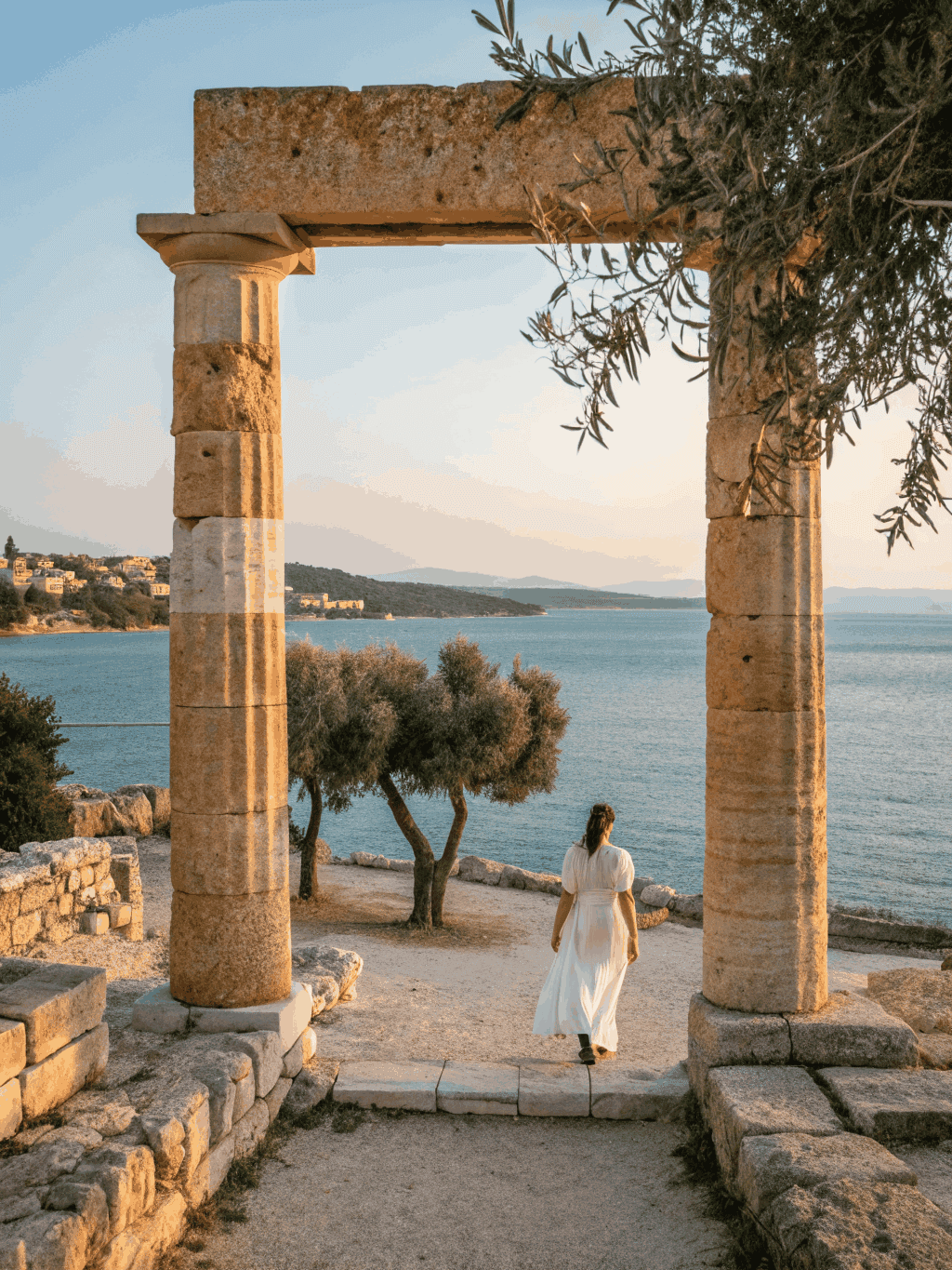 Classical Mediterranean stone archway overlooking a sunlit coastal harbor